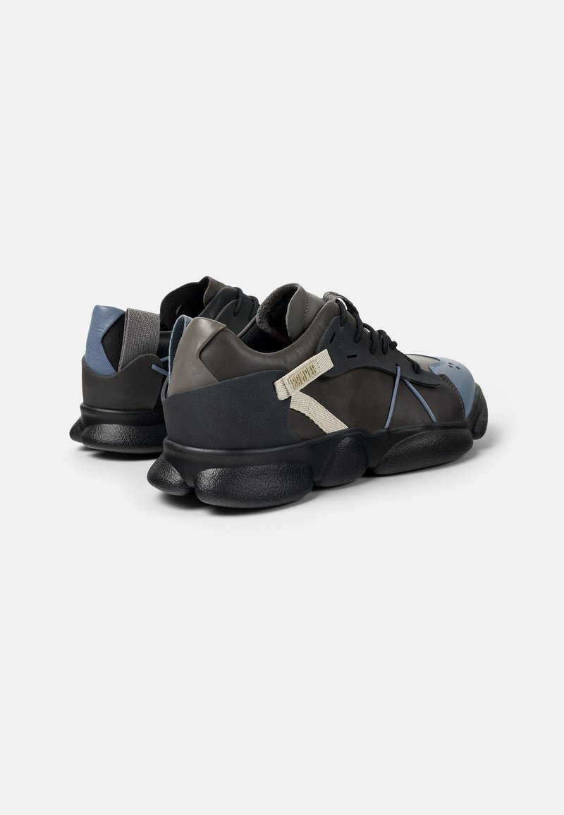 Smukłe czarne i szare sneakersy z zaokrągloną podeszwą, teksturowaną skórą i akcentami z siateczki, z unikalnymi blokami kolorów i wzorzystymi nakładkami.