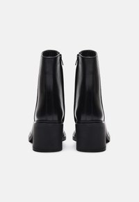 Svarte skinnankleboots med en glatt finish, rund tå og chunky hæl. Har en diskret glidelås bak for enkel påkledning.