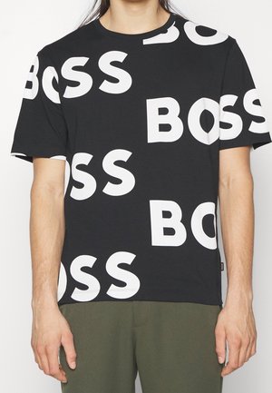T-shirt en coton noir avec un grand lettrage blanc "BOSS" de tailles variées, doté d'un col rond et de manches courtes, texture lisse.