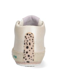 Zapato de cuero beige claro con un acabado texturizado. Presenta un acento marrón moteado en el talón y una suela suave con puntos verdes.
