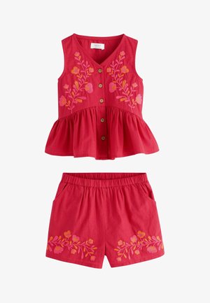 Top roșu fără mâneci, cu nasturi și peplum, brodat cu motive florale roz-portocalii, asortat cu pantaloni scurți cu talie elastică și broderie florală similară.