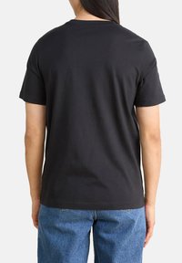 Schwarzes Baumwoll-T-Shirt mit kurzen Ärmeln und rundem Ausschnitt, Rückansicht. Verfügt über eine glatte Textur und einen lockeren Sitz.