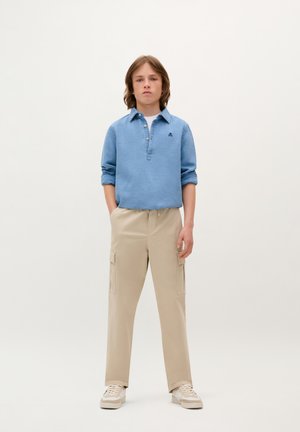 Helles blaues Langarm-Polohemd mit drei Knöpfen, kombiniert mit beigen Cargo-Hosen mit seitlichen Taschen und einer lockeren Passform.