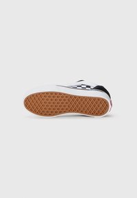 Svart-hvitt sneakers med gummisåle. Har en teksturert gummisåle, rutete mønster på overdelen og svarte detaljer langs sidene.