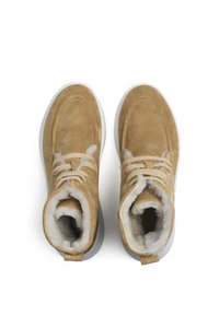 Tan suède enkellaarsjes met witte nepbont voering, ronde neus en platte rubberen zool. Heeft beige veters en stikselaccenten.