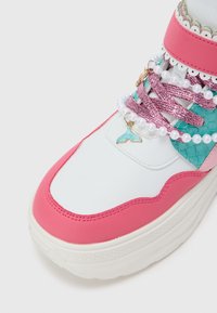 Ténis branco e rosa com detalhes texturizados, apresentando atacadores multicolores, detalhes em pérola e um pingente em forma de cauda de baleia.