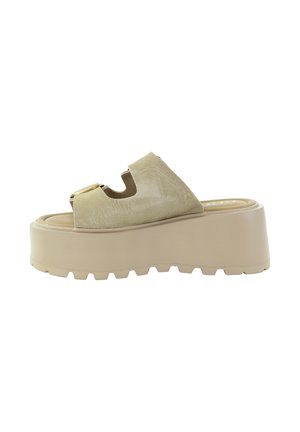 Beżowa sandałka na platformie z grubą gumową podeszwą, cholewką zamszową, odkrytymi palcami i dużą złotą klamrą na białym tle.