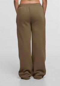 Braune Jogginghose mit weitem Bein, weichem Material und elastischem Bund. Keine sichtbaren Taschen; nahtloser Rückansicht.