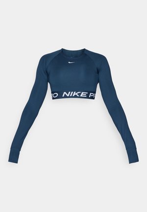 Crop top atletico a maniche lunghe di colore blu navy, realizzato in materiale elasticizzato, con logo Nike bianco e una larga fascia "NIKE PRO" nella parte inferiore.