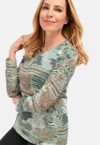 Langsleeve top met een textuur en een meerkleurig groen en bruin patroon. Beschikt over een ronde halslijn en aansluitende mouwen.