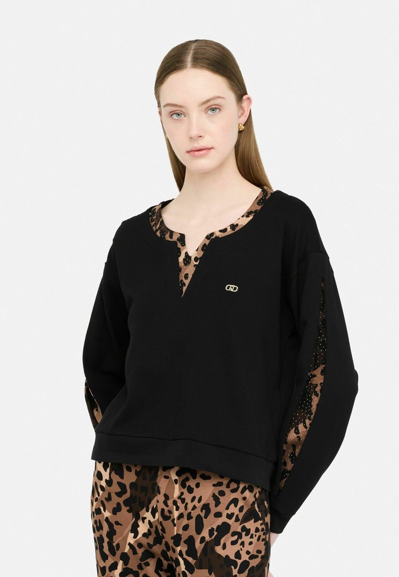 Felpa nera con scollo a V e dettagli in stampa leopardata. La felpa presenta maniche lunghe con pannelli laterali a fantasia e un dettaglio del logo dorato.