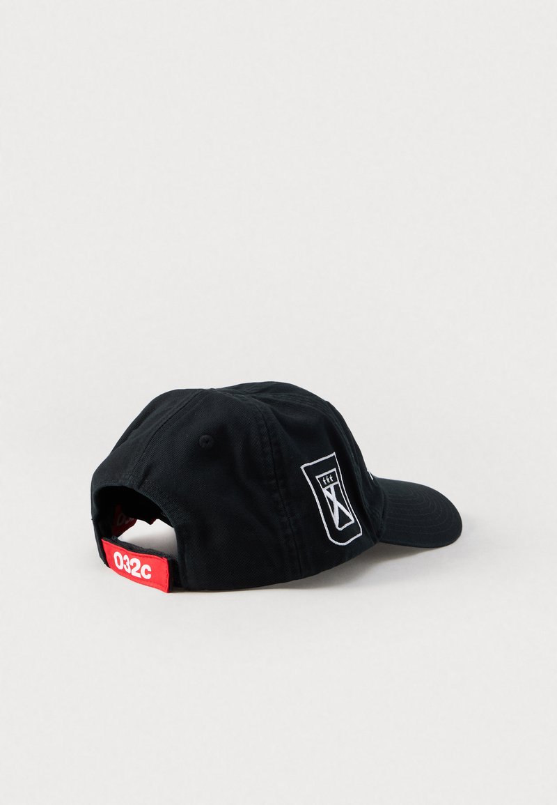 Cappello in cotone nero con visiera curva, logo a clessidra ricamato e un accento rosso con "032c" sulla cinghia regolabile.