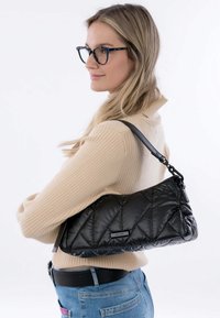 Zwarte gewatteerde schoudertas met een gladde textuur en een afneembare schouderband. Heeft een rechthoekige vorm en een merketiket aan de zijkant.