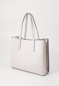 Sac fourre-tout en cuir rose clair avec une texture lisse, deux poignées plates, forme rectangulaire et surpiqûres contrastées sur les bords.
