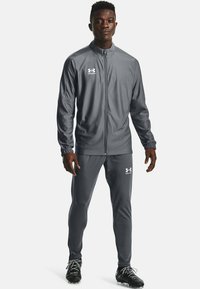 Tuta atletica grigia realizzata in materiale liscio, con giacca con zip e pantaloni aderenti. Logo bianco su entrambi i capi.