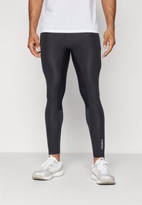 Sorte atletiske leggings lavet af glat, strækbart materiale, med en tætsiddende pasform og et lille hvidt "TECH FIT" logo på den nederste del af benet.
