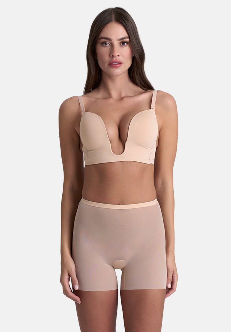 Reggiseno imbottito beige con scollatura profonda e spalline regolabili, abbinato a pantaloni corti a vita alta, trasparenti e con design senza cuciture.