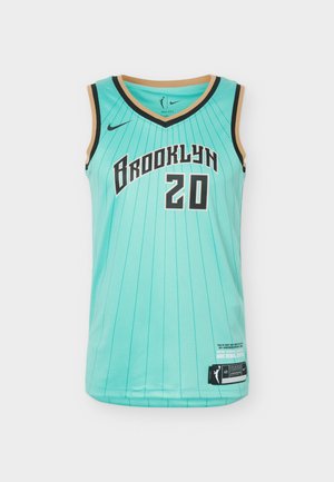 Fiatal férfi göndör hajjal, türkizkék Brooklyn kosárlabdamezben, 20-as számmal és fekete sport rövidnadrágban, egyszerű háttér előtt áll.