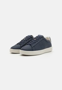 Mörkblå lädersneakers med rund tå, texturerade detaljer, kontrasterande vit gummisula och matchande snörning. Stiligt "H"-logotyp på sidan.
