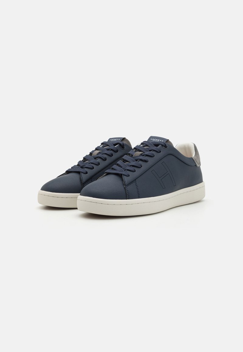 Baskets en cuir bleu marine avec bout rond, accents texturés, semelle en caoutchouc blanc contrastant et lacets ton sur ton. Logo "H" stylé sur le côté.