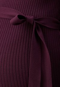 Plum ribbed fabric with a tied bow accent at the waist, showcasing a textured design and form-fitting shape.
