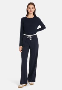 Marineblaue Rippstrickpullover mit langen Ärmeln, kombiniert mit marineblauen weiten Hosen mit einer weißen Kordelzugtaille. Bequemer Stoff und.Lockere Passform.