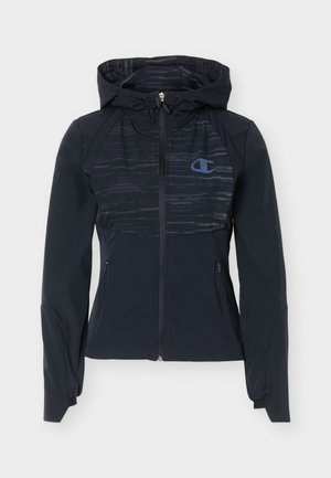 Μαύρο μπουφάν με κουκούλα και φερμουάρ, μακριά μανίκια, ελαστικά μανσέτες, δύο τσεπάκια με φερμουάρ στα πλάγια και διακριτικό υφασμάτινο μοτίβο στο μπροστινό μέρος.