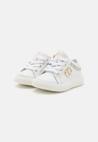 Sneakers bianche realizzate in materiale sintetico, con accenti dorati, borchie decorative e punta rotonda. Lacci e dettaglio del logo sulla linguetta.