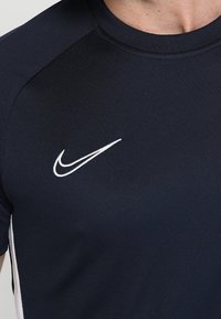 Close-up of a person wearing a black athletic shirt with a white Nike swoosh logo on the upper chest.