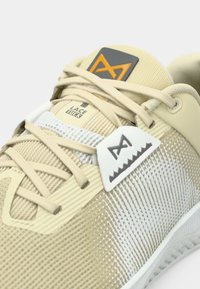 Μπεζ αθλητικά παπούτσια με υφαντό πλέγμα στο επάνω μέρος, λευκές λεπτομέρειες και γκρι λογότυπο. Διαθέτουν επίπεδες κορδόνια και μαλακή επένδυση στον αστράγαλο.