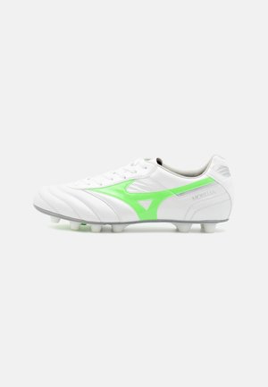 Witte voetbalschoenen met een glad leren bovenwerk, groene accenten en een geribbeld ontwerp; beschikt over zes conische noppen voor grip.