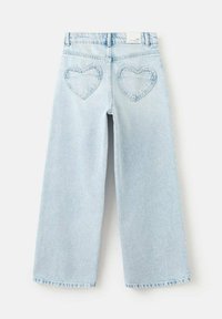 Jean large bleu clair avec couture en forme de cœur sur les poches arrière. Le tissu a une finition douce et texturée. Conception taille haute avec cinq poches.