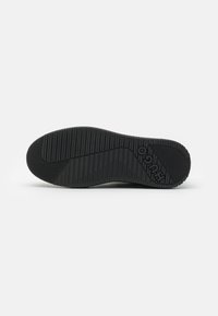 Sole in gomma nera con superficie texture, caratterizzata da scanalature verticali e orizzontali e logo del marchio in rilievo.