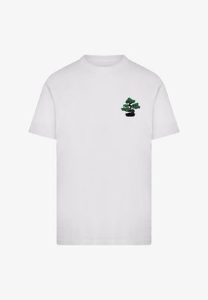 T-shirt blanc à manches courtes avec un petit motif d'arbre bonsaï vert sur la partie supérieure gauche de la poitrine.