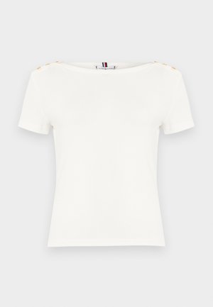 Haut blanc pour femme à manches courtes avec encolure bateau et boutons dorés sur les deux épaules, présenté sur un fond clair uni.