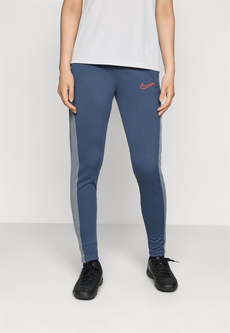 Mørkeblå leggins med grå sidestykker, med en rød Nike-logo. Laget av elastisk stoff, med en tettsittende design og elastisk midjebånd.