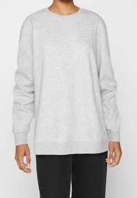 Vaaleanharmaa, pitkähihainen collegepaita pyöreällä pääntiellä, resorit hihansuissa ja helmassa, jossa pieni logo rinnassa. Puuvillasekoitemateriaali.