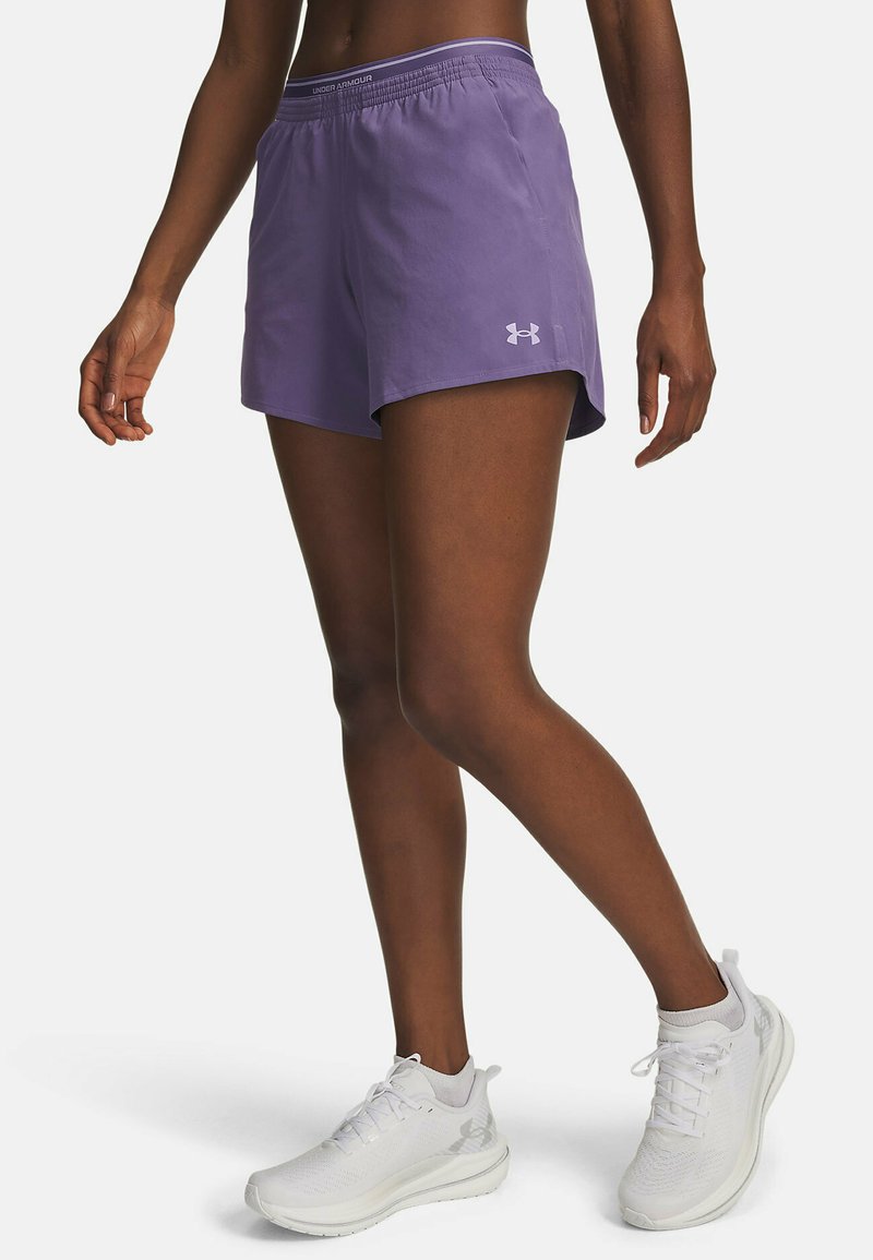 Purple athletic shorts with an elastic waistband and Under Armour logo. Worn with white athletic shoes on a model.