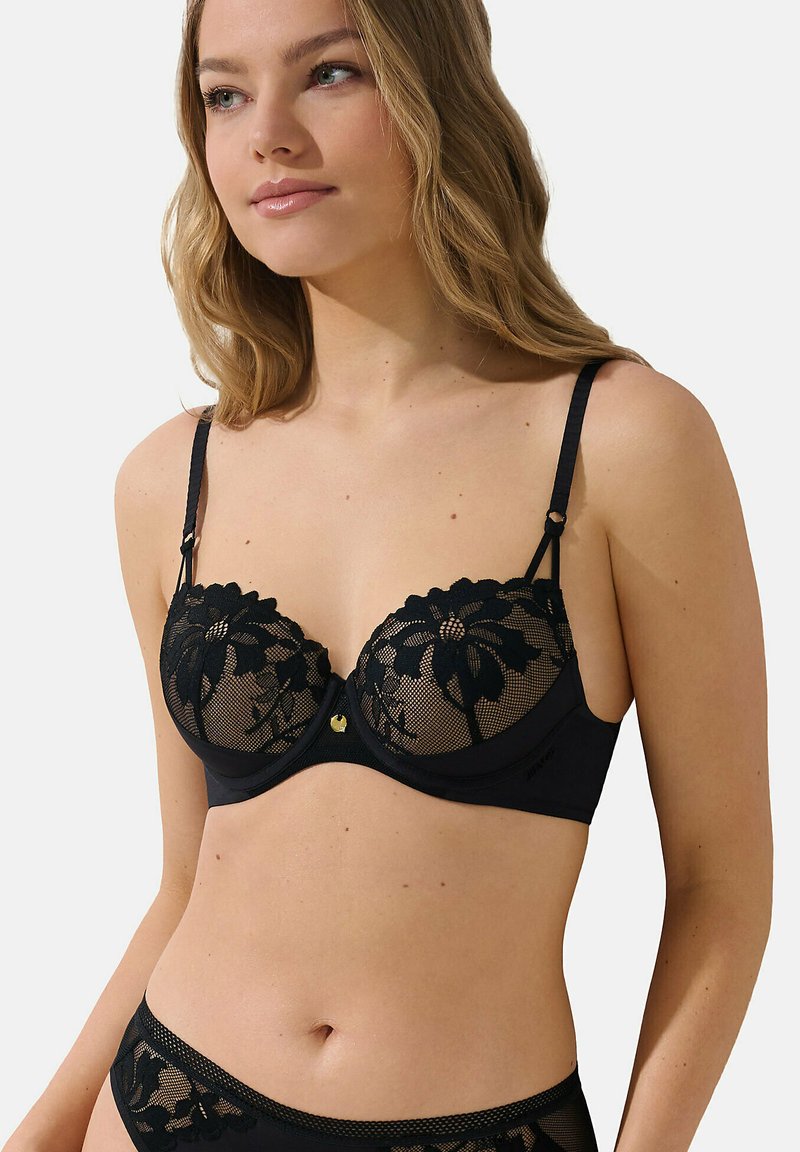 Zwart lingerieset met een beha met kantbloemdetails, doorschijnende cups en verstelbare bandjes. Het gladde materiaal zorgt voor een contrast met het kant.