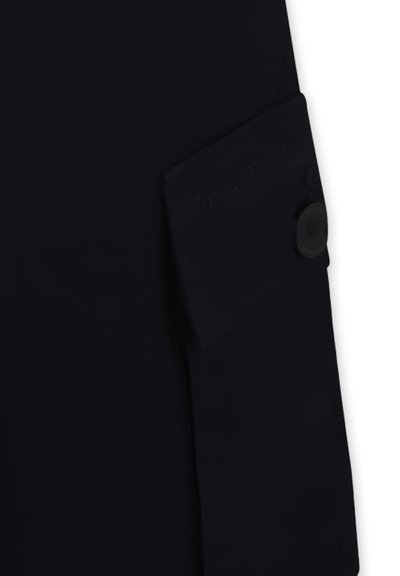 Zwarte jassenstof met een voorzak en een ronde zwarte knop. De zak heeft reliëfletters, wat textuur aan het ontwerp toevoegt.