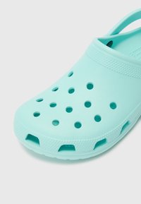 Turquoise clogs made of lightweight plastic, featuring ventilation holes and a back strap. Smooth surface with a textured band around the top.