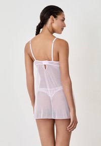 Negligee trasparente rosa con pois bianchi, spalline regolabili e dettaglio a occhiello sulla schiena. Tessuto morbido e leggero con bordo in pizzo.