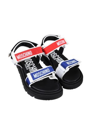 Sandali bianchi con cinturini regolabili rossi e blu, con il logo "Moschino" ben visibile. Suole in gomma nera e soletta imbottita.
