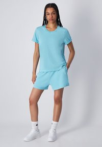 Maglietta in cotone azzurro chiaro e pantaloni corti abbinati, maniche corte, colletto rotondo, design minimale, abbinati a sneaker bianche e calze.