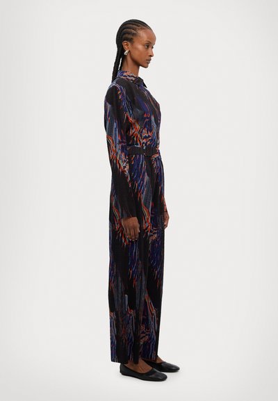 Vestido largo negro con patrones abstractos en azul, rojo y naranja. Presenta mangas largas, una cintura ceñida con cinturón y una silueta recta.