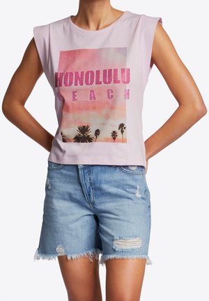 Person trägt ärmelloses hellrosa Croptop mit dem Schriftzug "Honolulu Beach" und Palmen-Grafik, kombiniert mit hellblauen Denim-Shorts mit ausgefranstem Saum.