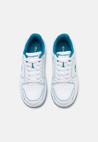 Vita sneakers med blå accenter, tillverkade av syntetiskt material. Funktioner inkluderar perforerad tå, vita snörningar och Champion-logotyp.