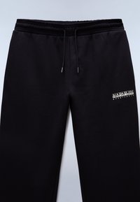 Black sweatpants made of soft fabric, featuring an elastic waistband with drawstrings and a white logo on the left thigh.