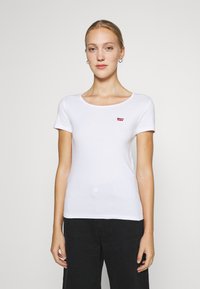 Tricou alb din bumbac cu decolteu rotund și mâneci scurte. Prezintă un mic logo roșu pe piept. Textură netedă, design ajustat.