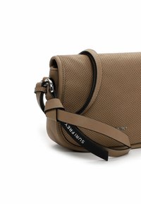 Borsa a tracolla in pelle perforata color tan con una tracolla nera, caratterizzata da una forma tondeggiante e dettagli in metallo argentato ben visibili. Logo visibile sulla tracolla.